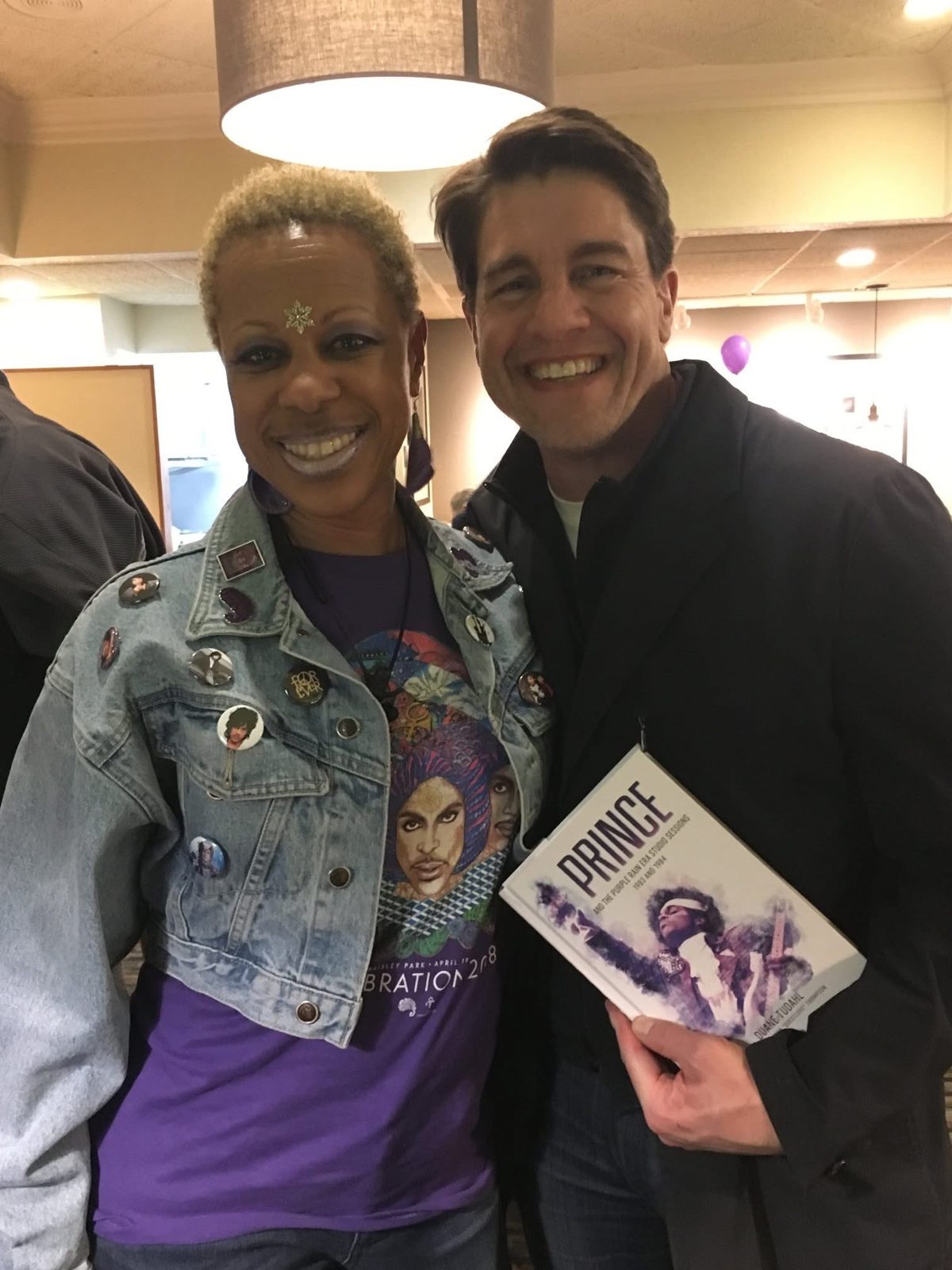 Denim jacket with pins and a Celebration 2018 shirt, with the Prince book