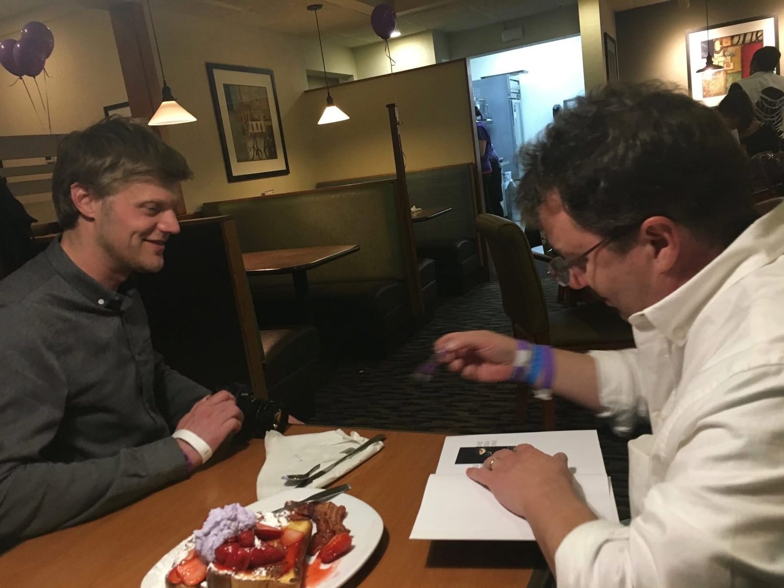 Book signing beside a plate of strawberries and purple whipped cream