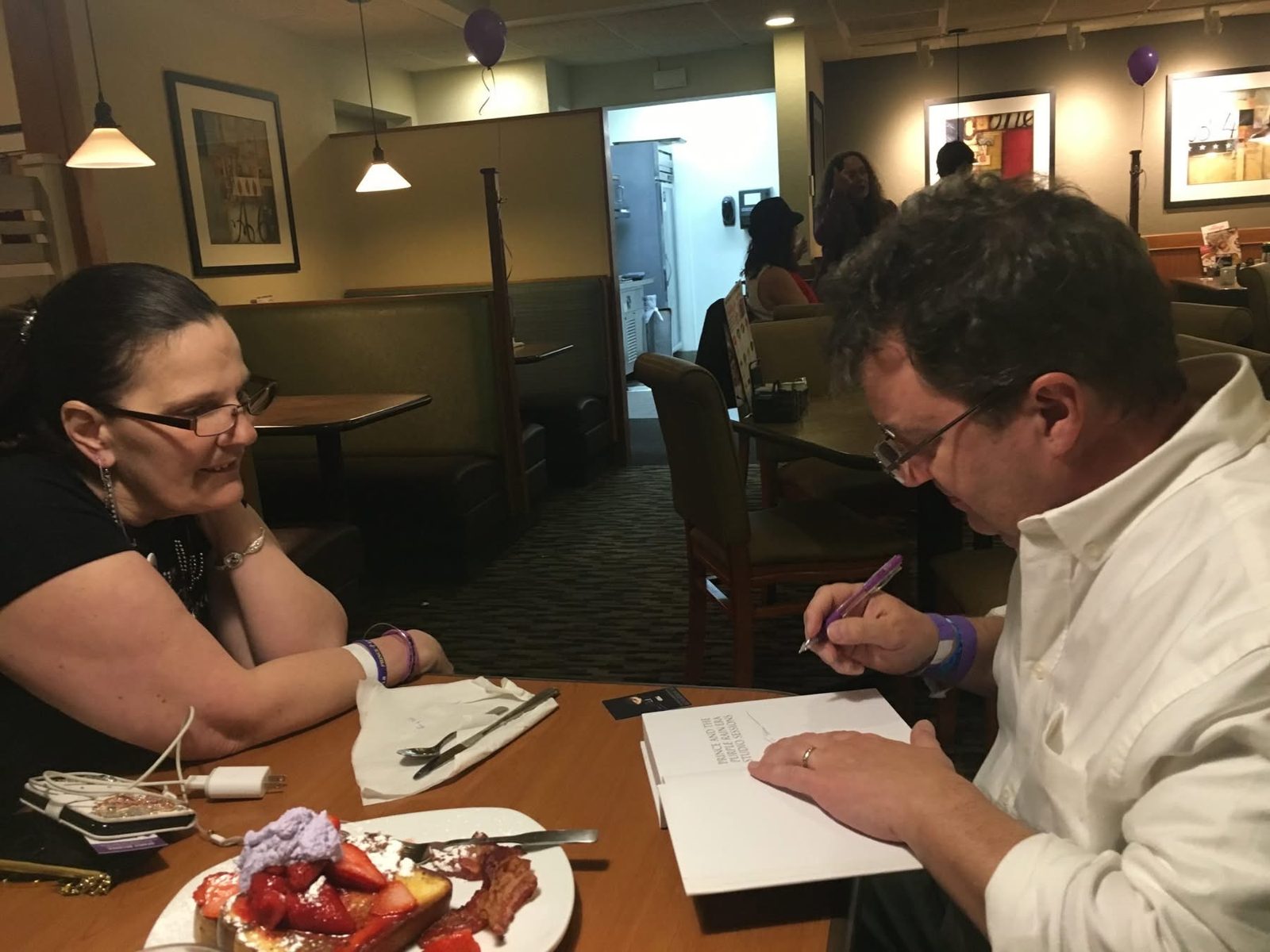 Signing a book, strawberry plate on the table